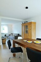 Wooden dining table with black chairs, wooden cabinet and sofa in dining room