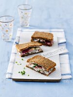 Wholemeal sandwich with turkey breast, chives, beetroot sprout on chopping board