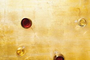 Glasses of white wine and red wine on a golden surface (seen from above)