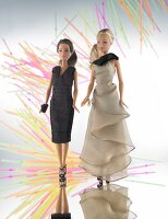 Two beautiful barbie dolls wearing black and beige evening dresses