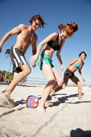 junge Leute am Strand, haben Spaß, spielen Fußball