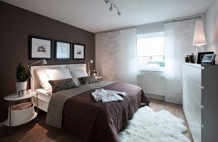 View of white and brown bedroom with double bed, rug and photo frames