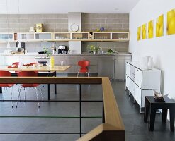 A spacious, modern kitchen with stainless steel work tops and maple wood wall shelves and dining table