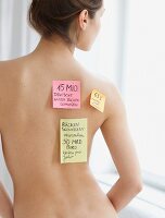 Rücken einer Frau mit Aufklebern: Thema Rückenschmerzen
