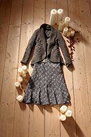 Grey hole knitwear cardigan, wool skirt and candles scattered on wooden floor