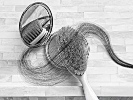 Close-up of hair brush with strands and mirror, black and white