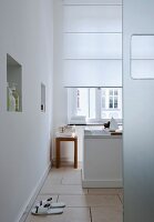 A white bathroom with a window, a free-standing bathtub, a tiled floors and a wall niche used as storage