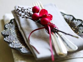 A place setting decorated for Christmas with a napkin, a twig and baubles