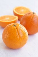 Close-up of two whole and two halved oranges on white background
