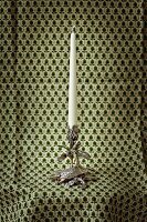 Silver plated candle stand with candle against green cloth