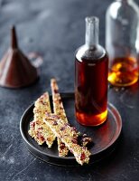 A bottle of caramel syrup and sesame brittle with cranberries