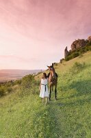 Woman with horse standing on mountain slope in Franconian Switzerland, Bavaria, Germany