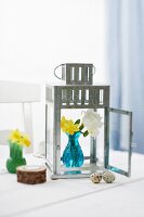 Easter decorations with a zinc garden lantern, narcisi in a vase and quail's eggs