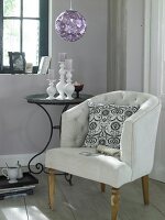 White delicate chair with cushions and side table with vase