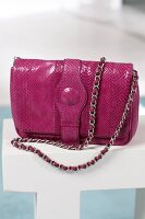 Close-up of pink python leather bag with chain strap
