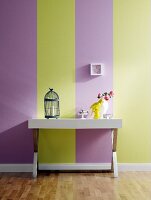 Table with bird cage and flower pot against striped wallpaper