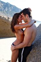 Side view of semi dressed young couple embracing and kissing each other on beach