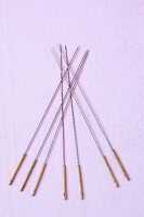 Close-up of acupuncture needles on purple background, overhead view