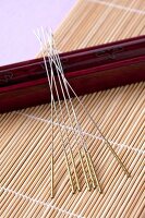 Close-up of acupuncture needles and wooden mat on purple background
