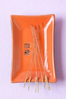 Acupuncture needles in an orange and black tray