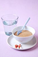 Close-up of glass of water and bowl of alternative medicine and pills on plate
