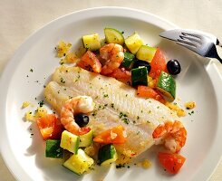 Close-up of cod and shrimp with zucchini ragout on plate