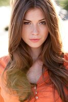 Portrait of beautiful woman with brown hair wearing orange top