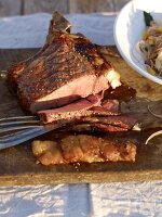 Grilled Argentinean steak sliced on wooden platter with onion salad in bowl