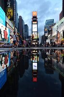 Reflection of illuminated advertisements on puddle at Times Square in New York, USA