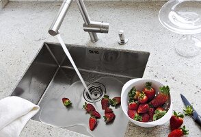 Bowl of strawberries kept aside after being washed under running water in sink