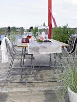Tisch mit Geschirr, Stühle, Terrasse am Wasser