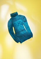 Turquoise sweater with turtleneck on yellow background