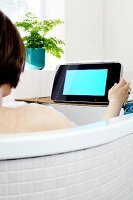 Woman in bathtub operating waterproof LCD TV
