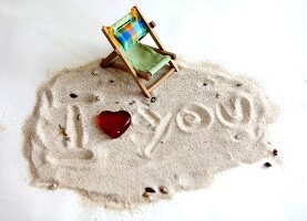 I Love you written in the sand with beach chair