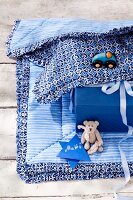 Close-up of patterned baby blanket with ruffle trim, gift and toys