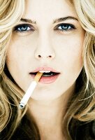 Portrait of beautiful blonde woman holding cigarette, close-up