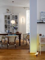 A view into an open living room with a dining table, wicker chairs and a cabinet