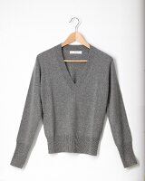 Close-up of gray knitted sweater on hanger against white background