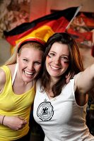 Portrait of two ecstatic women at a football game with Germany flag in background