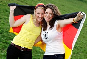 Portrait of two beautiful women holding German flag and smiling
