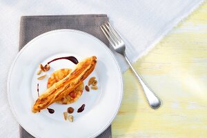 Goat cheese in puff pastry with apple confit, nuts and pear sauce on plate, overhead view