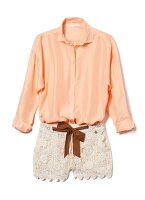 Close-up of peach silk blouse and lace shorts on white background