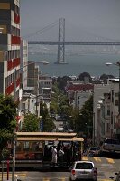 People travelling in tram and Bay bridge in background at San Francisco, California, US