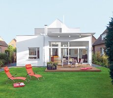 View of house in white colour with garden and sun loungers