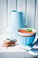 Spicy tomato soup with grilled bread in a soup bowl served with bread and cream cheese