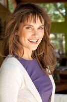 Portrait of pretty brown haired woman wearing purple top and white cardigan, smiling