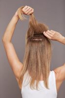 Rear view of blonde woman back combing her hair