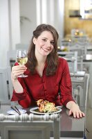 Frau mit langen braunen Haaren und roter Bluse im Restaurant