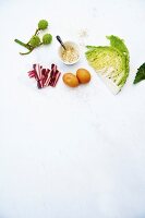 Different vegetable with Savoy cabbage, bacon, chestnuts and eggs on white background
