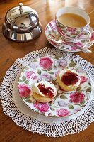 Scones on saucer with rose designs, tea cup and saucer on wooden table